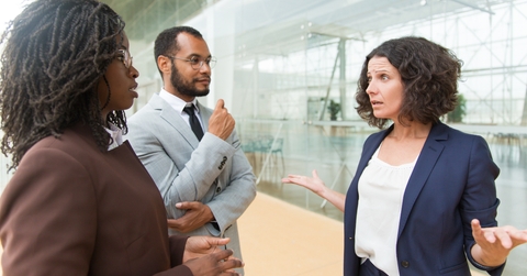man and women standing at outdoor glass wall talking to each other