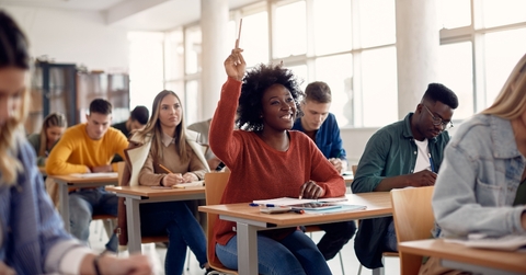 student raising arm to answer question while attending class