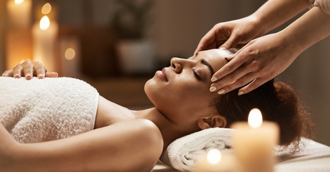 woman enjoying face massage in spa salon