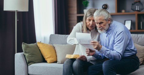 senior husband showing banking paper to confused elderly wife