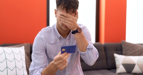 man holding credit card with worried expression 