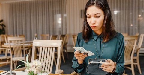 anxious woman at restaurant taking out money from wallet