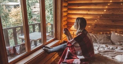 woman holding cup of coffee while relaxing inside log cabin