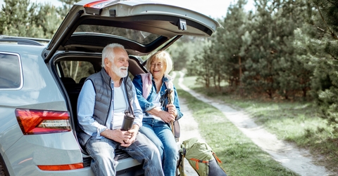 senior couple sitting at the car trunk