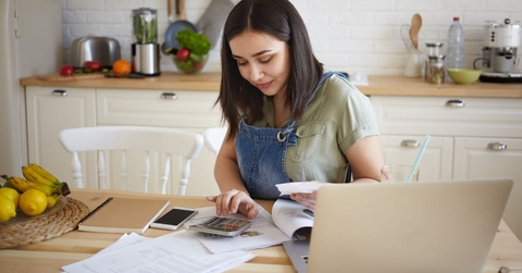 woman sitting on table at home with papers and laptop calculating home budget