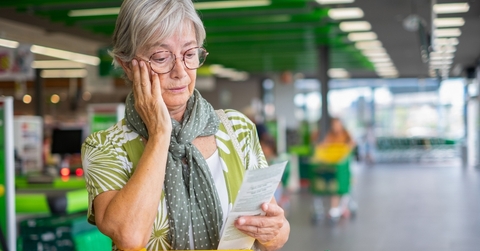 senior woman in the supermarket checks her grocery receipt