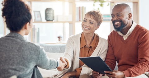 African American couple shaking hands with female financial advisor at home