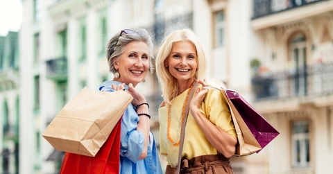 senior women standing in street with shopping bags posing for picture