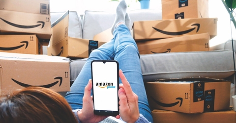 woman using smartphone relaxing in her room while surrounded by Amazon Prime delivery boxes