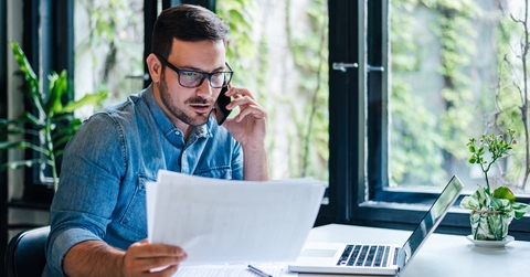 manager reviewing documents while talking on smartphone