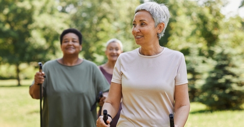 active senior woman walking with poles and smiling outdoors
