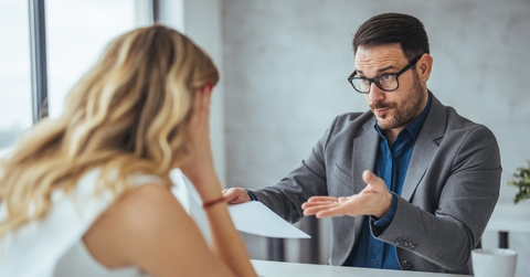 businessman holding papers arguing with young business woman at office