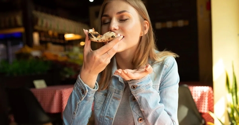 woman sitting in resturant taking slice of pizza