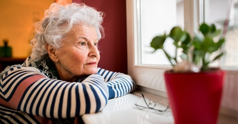 sad senior woman looking through window