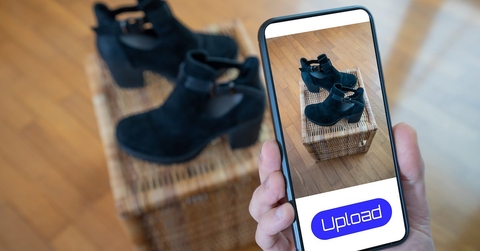 A reseller takes a photo of a pair of shoes for sale using their smartphone. 