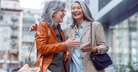 two beautiful senior females laughing in street