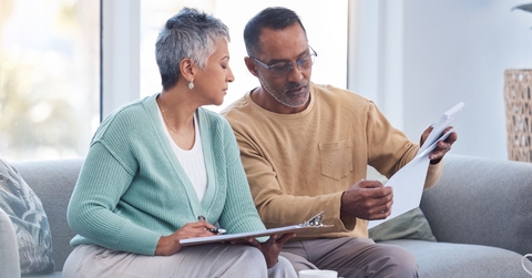 senior couple sitting on couch at home reviewing bills and financing retirement plan at home