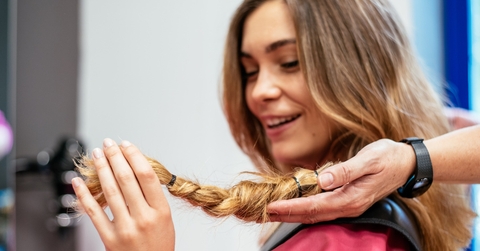 woman at hair salon cutting her hair short to donate it to cancer patients