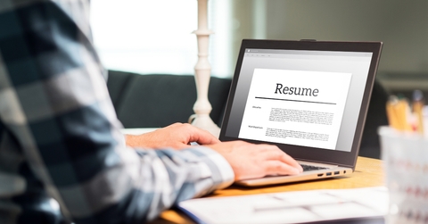 man writing resume and cv in home office with laptop