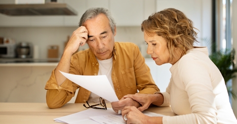senior spouses sitting at table full of papers