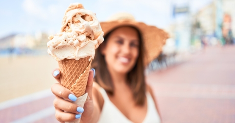 woman showcases delicious ice cream cone.