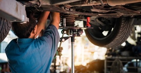 Mechanic inspecting car from below