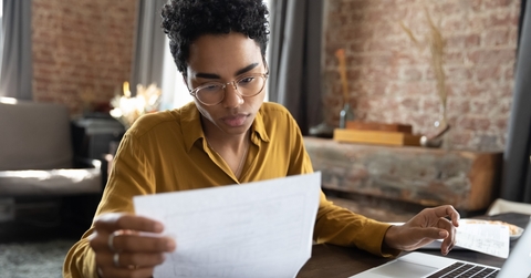 woman in eyeglasses looking through paper
