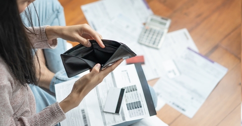woman staring empty wallet with bills