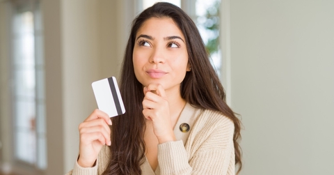 woman holding card while thinking