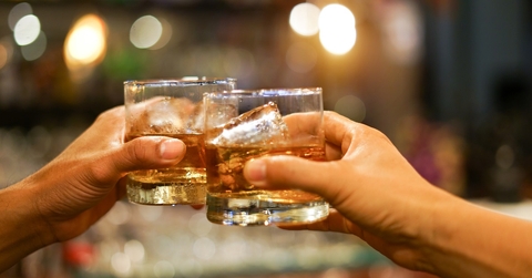 two men clinking glasses of whiskey