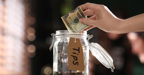 woman putting banknotes into glass jar