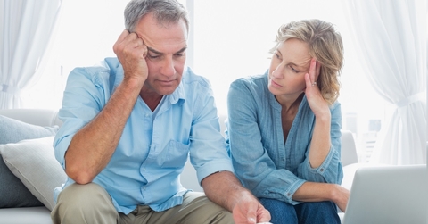 worried senior couple reviewing bills together