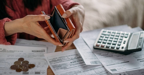 Close-up of woman's hands with empty wallet and utility bills