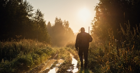 hunter with shotgun walking through trail