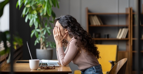 stressed overworked female employee covering face