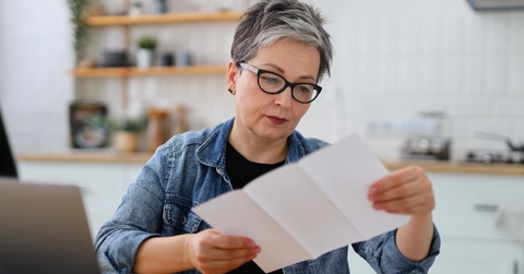 senior woman reading bills in kitchen