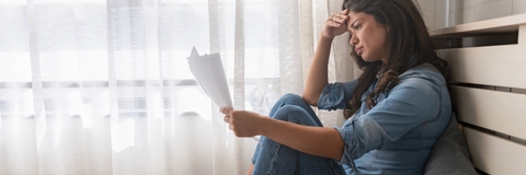 stressed woman holding financial papers