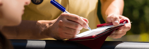 Police officer writing speeding ticket to driver