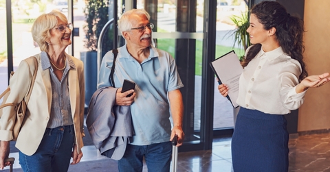 cheerful hotel receptionist greeting senior couple
