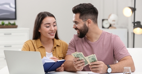 young couple counting money at home