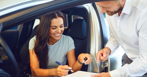 happy woman buying car at showroom