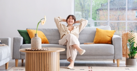 happy woman relaxing on grey sofa