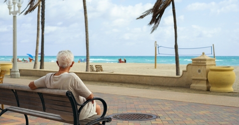 retired man sitting on bench at beach