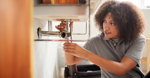 Female plumber fixing bathroom sink