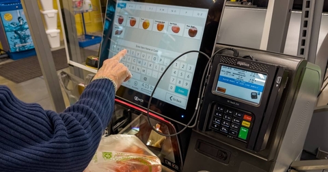 shopper using self service checkout at grocery store