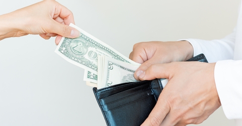 taking dollar bills out of his black purse