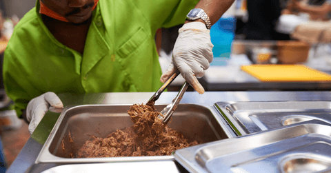 Chef serving pulled pork with tongs