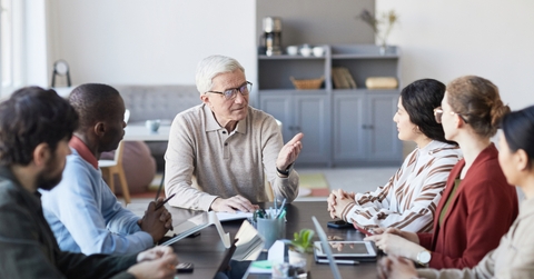 senior businessman talking to group of people during meeting