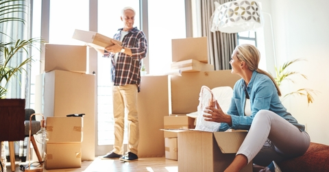 couple packing boxes together in their home