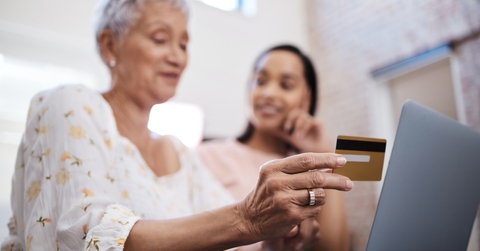 senior woman using laptop and credit card with her daughter